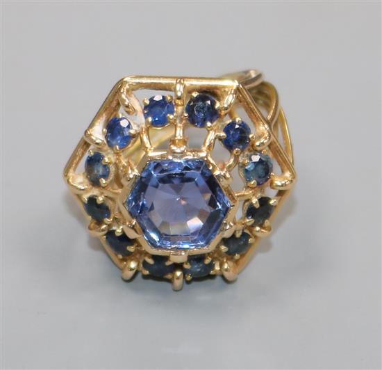 A yellow metal and sapphire set hexagonal openwork cluster ring, size J.